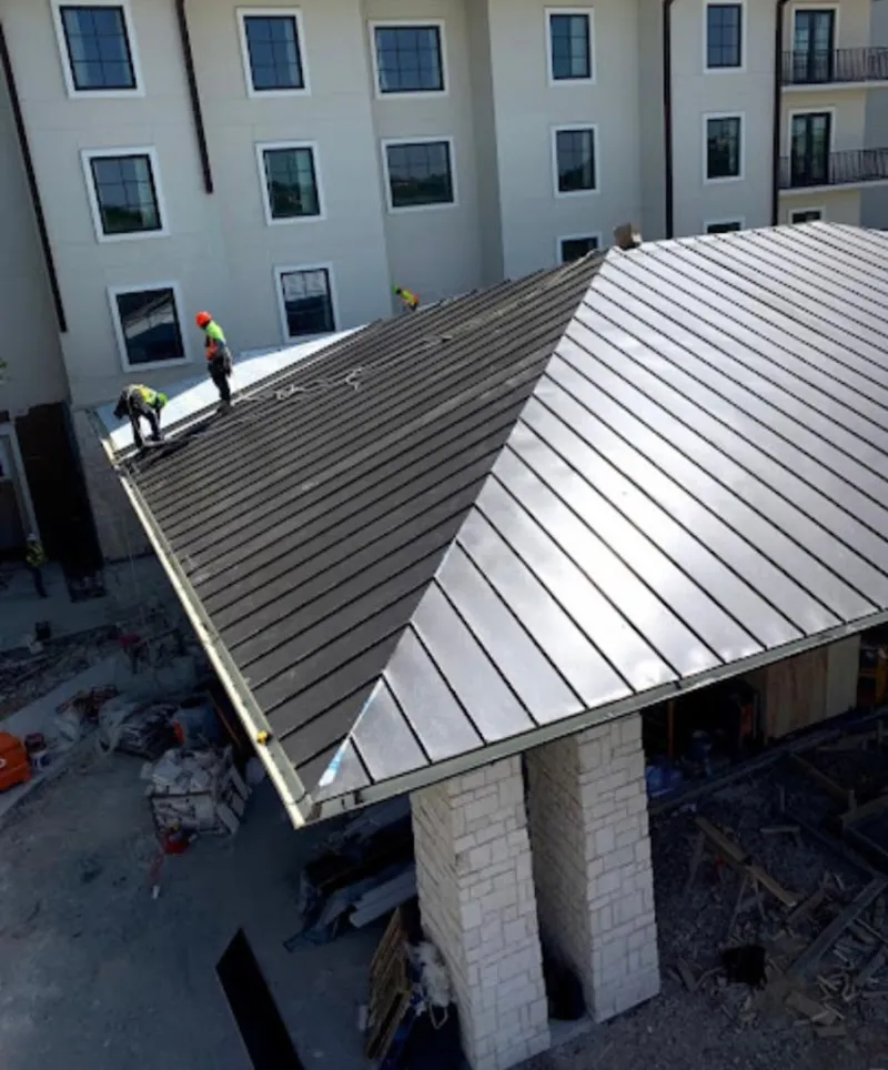 Crew installing standing seam metal roof panels on a commercial project in Woodlawn